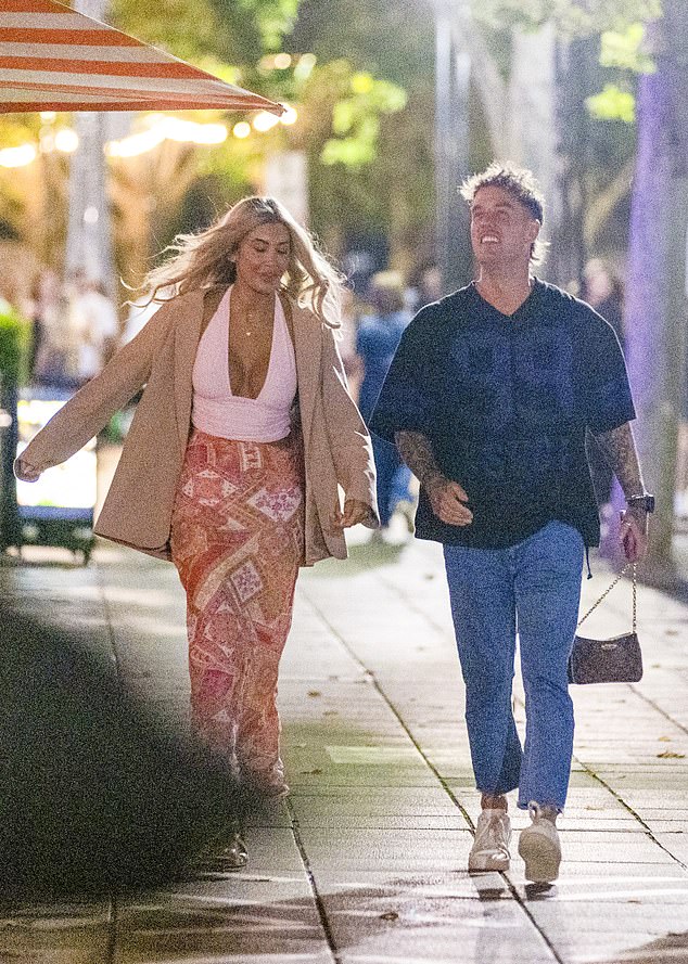 She layered the look with an oversized beige blazer and completed the outfit with strappy white heels and a small designer shoulder bag