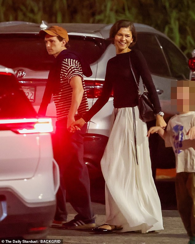 Holland kept it casual in loose trousers and striped shirt along with a baseball cap and a sweater flung over one shoulder