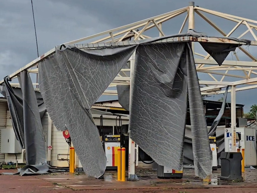 The protective roof of a petrol station is ripped into large pieces.