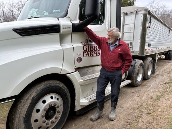 Chris Gibbs stands in front of his semi-truck. On the driver's side door is his brand, which reads, "Gibbs Farms."