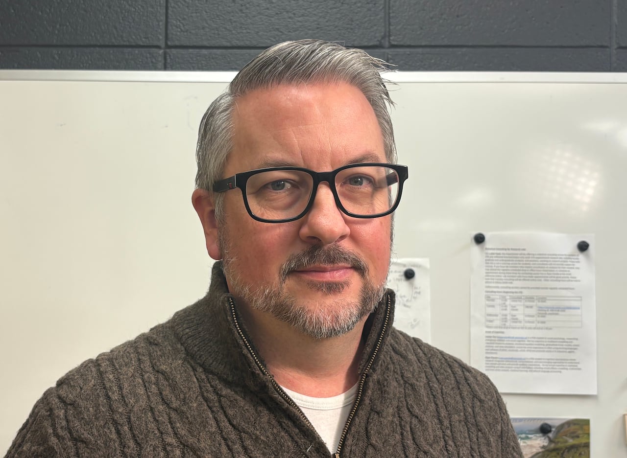 A man wearing a sweater and glasses poses for a photo