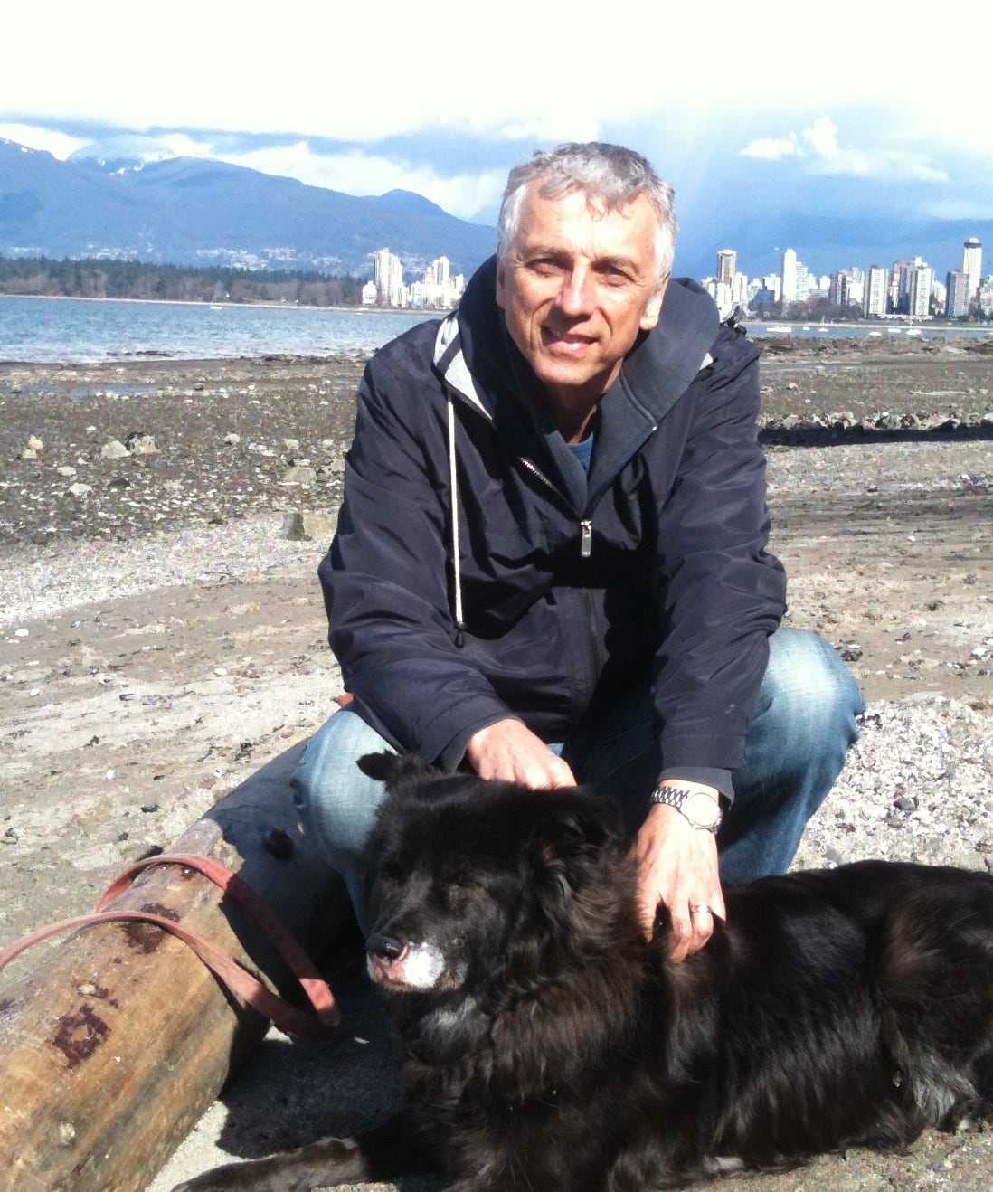 Man crouching petting a dog.