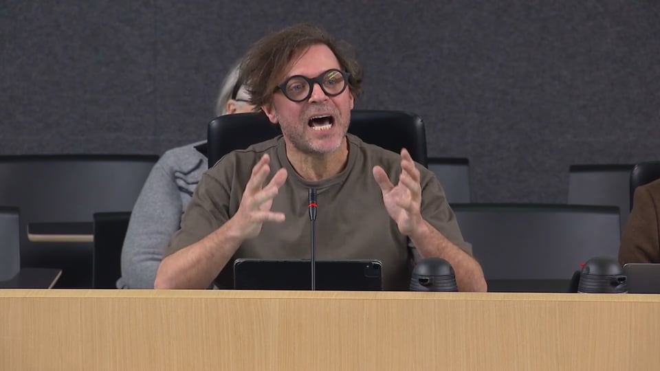 Christain Lapointe, a theatre director, is seen with a frustrated expression while seated before a microphone testifying at a National Assembly hearing.