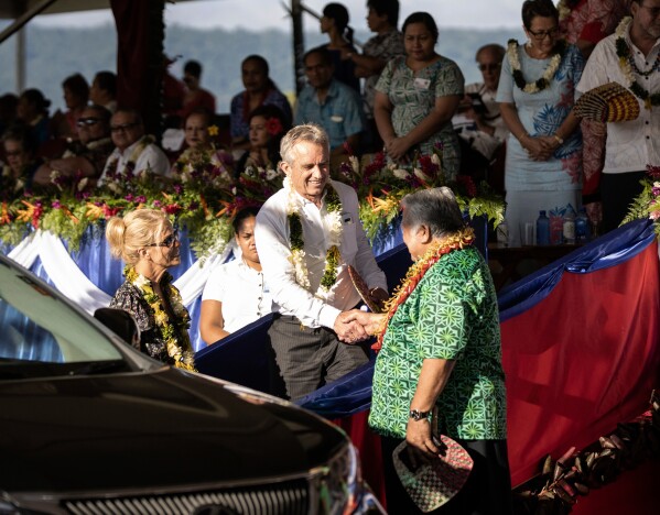 Prime Minister Tuilaepa Sailele Malielegaoi, foreground right, shakes hands with Robert F. Kennedy Jr. at the the 57th Independence Celebration in Mulinu'u, Samoa, June 1, 2019. At foreground left is Kennedy's wife, actress Cheryl Hines.(Misiona Simo/Samoa Observer via AP)