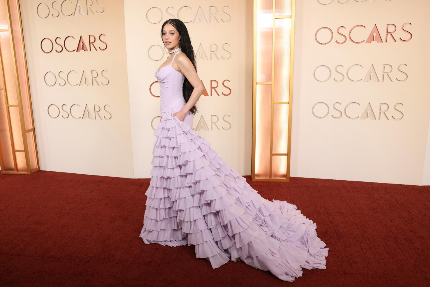 Chase Infiniti arrives on the red carpet in a lavendar tiered ruffled gown with train.