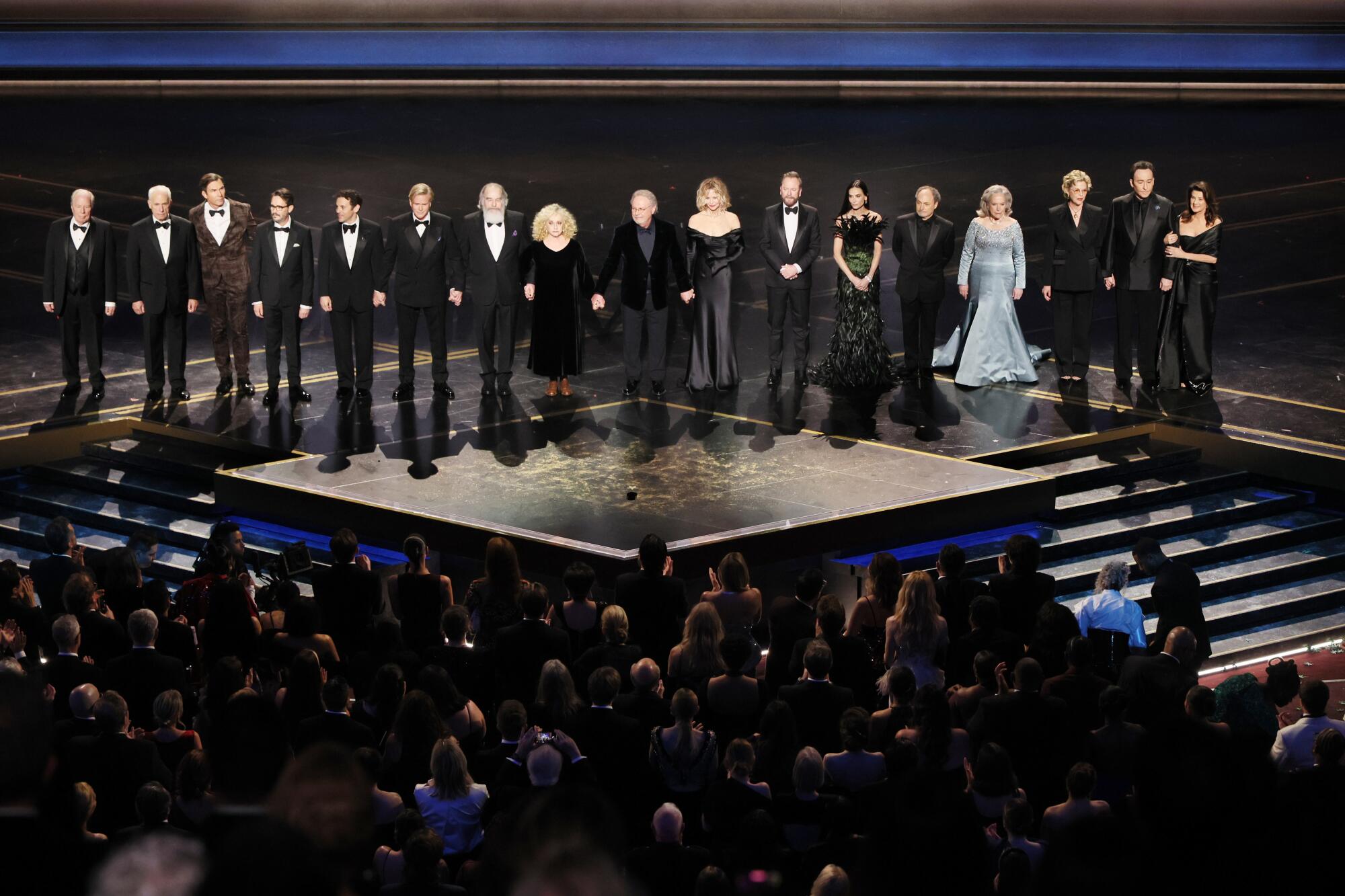 Actors stand on the Oscar stage. 