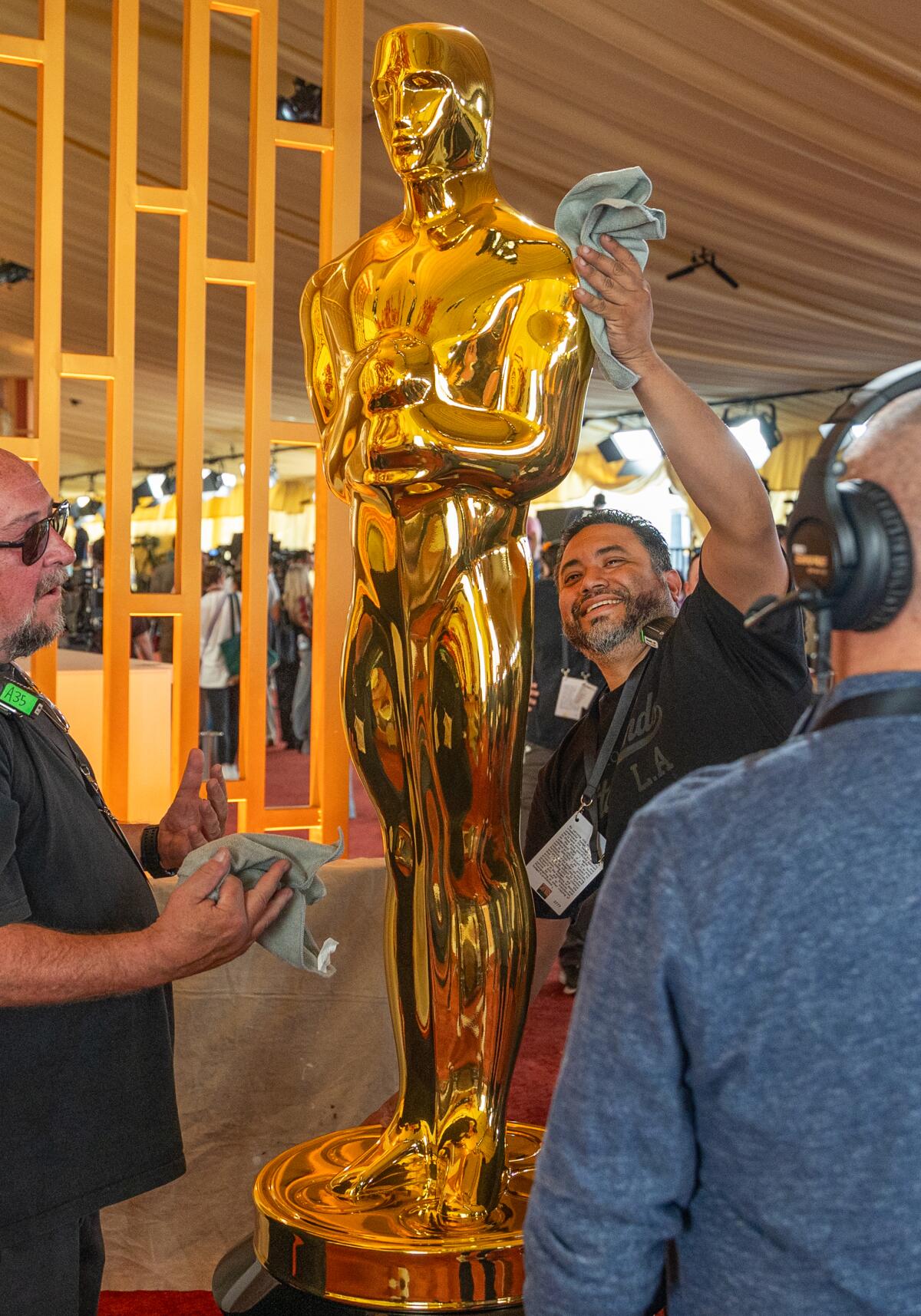 Workers polish a decorative Oscar statue on the red carpet