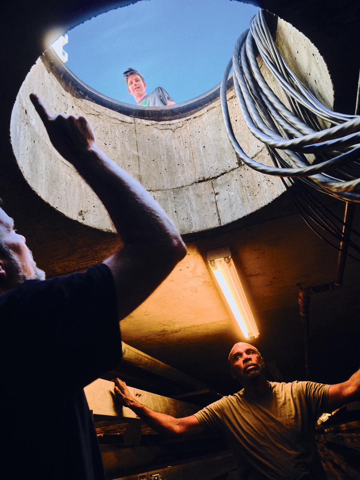 Electricians run cables through underground manholes at the Dolby Theatre.