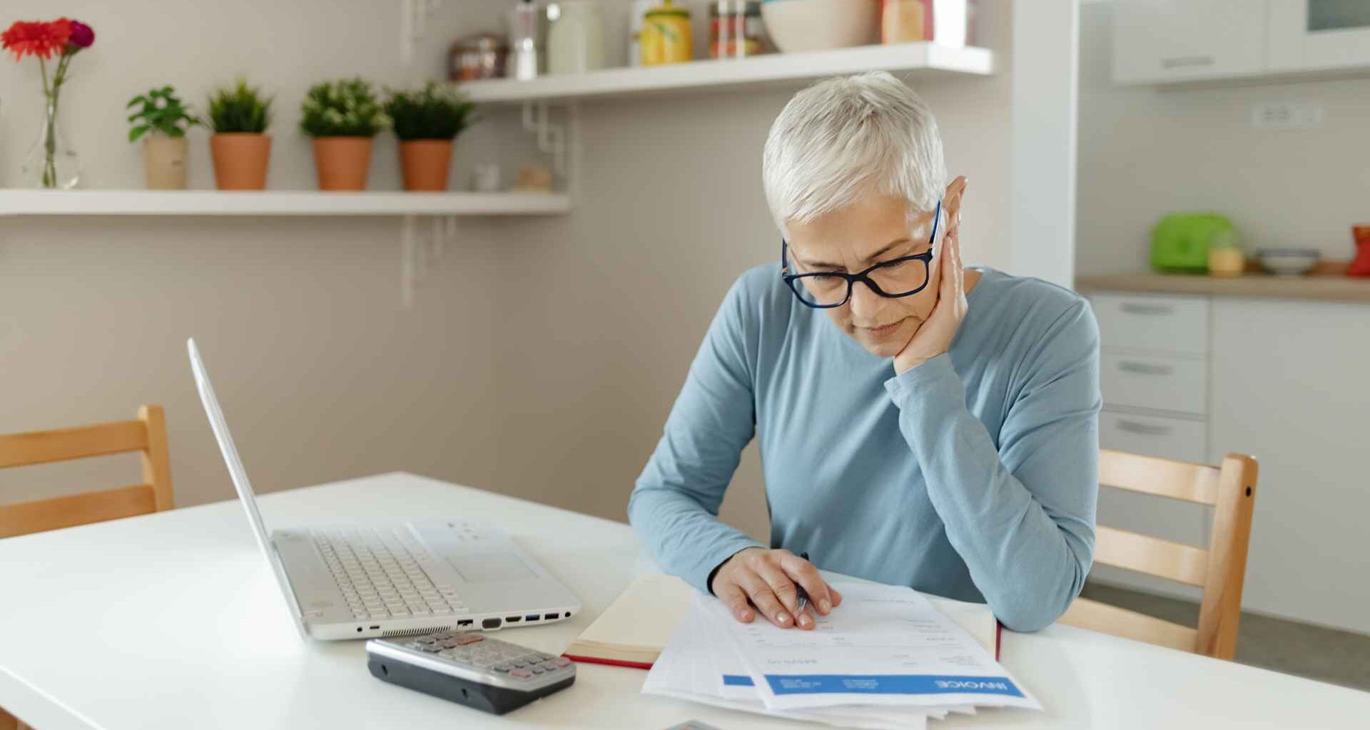 A woman puts her hand on her face as she looks at paperwork.
