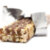 This photo shows a granola bar with its wrapper open and partially pulled back. It's lying on a white surface and against a white background.