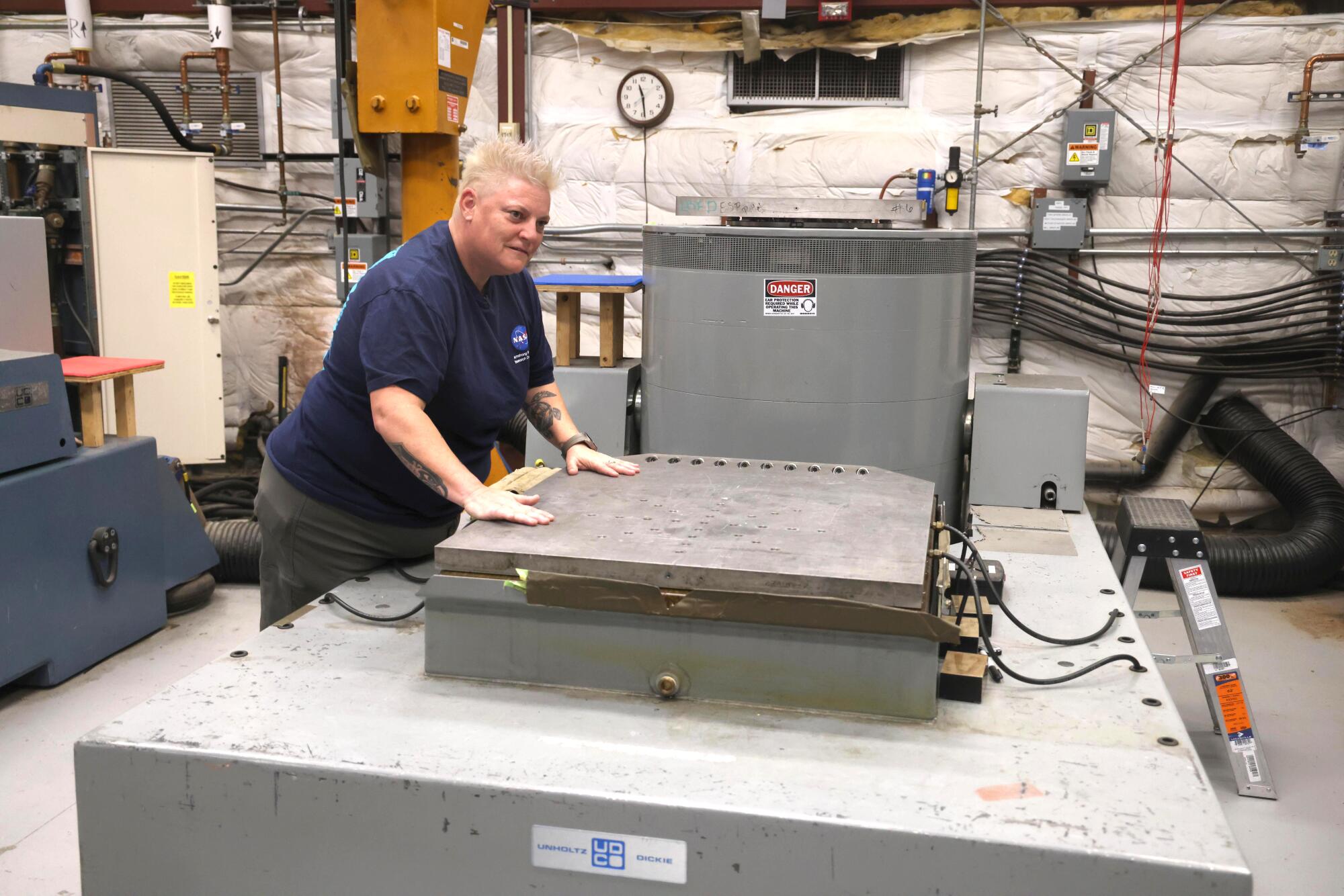 Environmental Test Technician Cryss Punteney places her hands on the Unholtz Dickie vibration table
