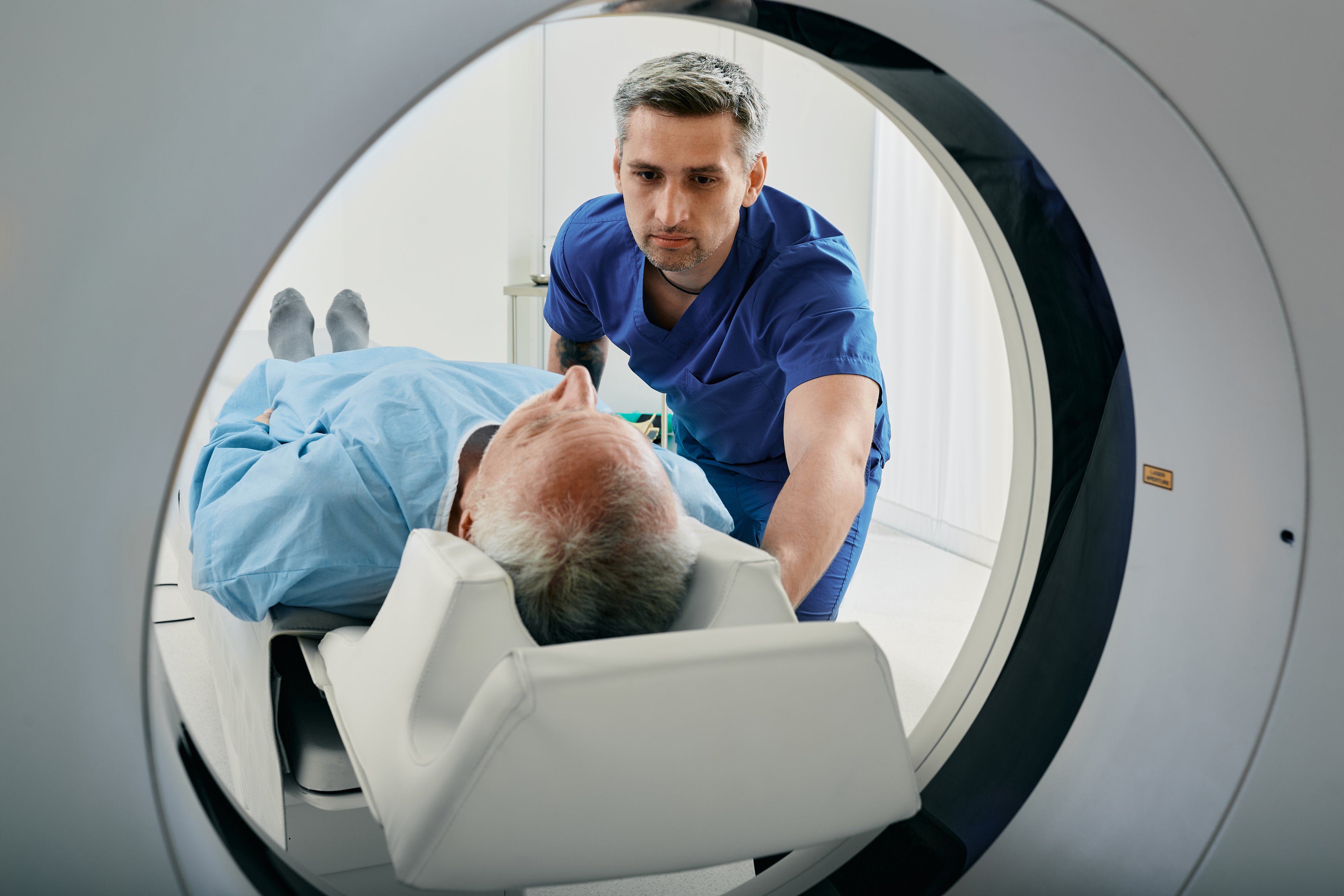 Medical professional assisting a person in an MRI machine.