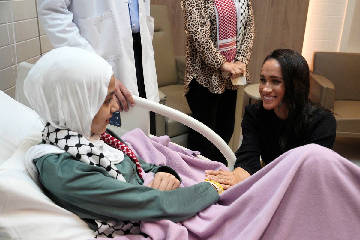 Meghan holds the hand of Maria, a 14-year-old burn victim from Gaza at a hospital in Jordan