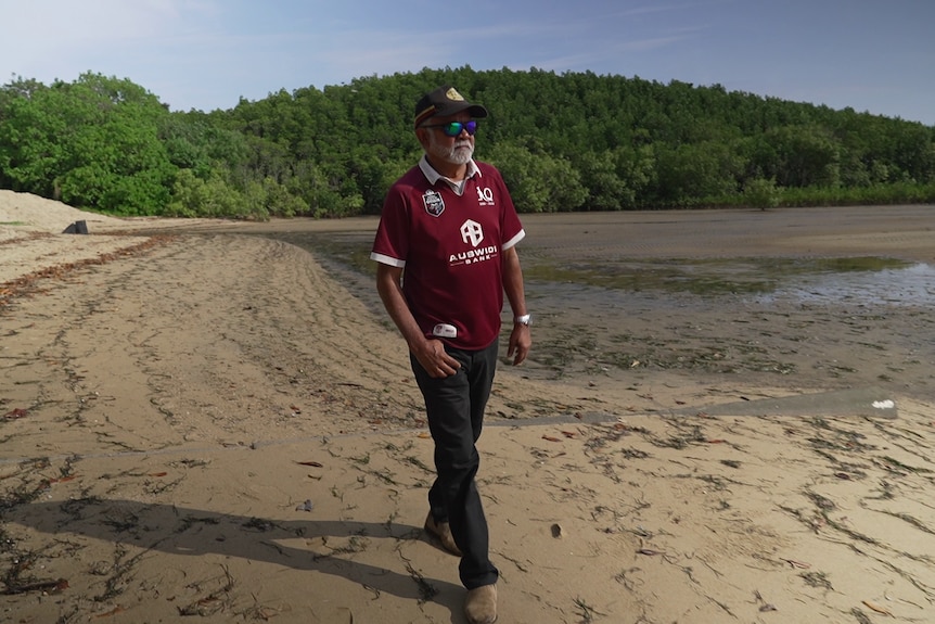 A man walking across mud flats.