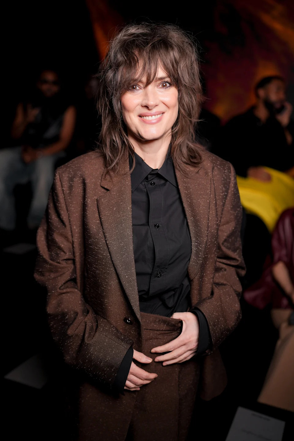 Person in a stylish, textured suit jacket and black shirt, smiling at an event