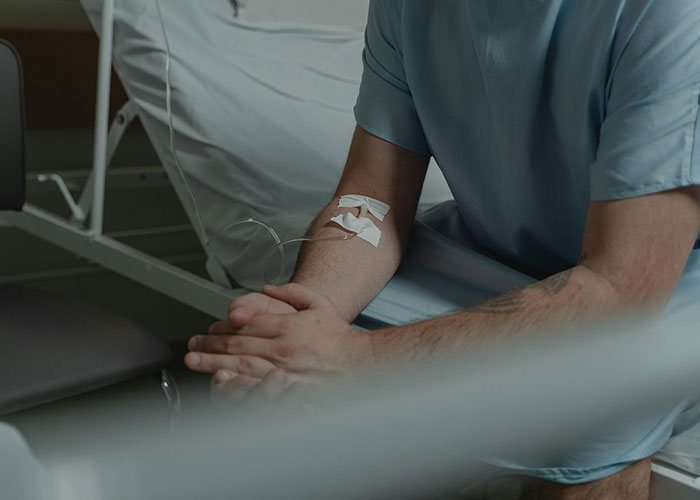Patient sitting on hospital bed with IV drip attached to arm, illustrating medical secrets in a clinical setting.