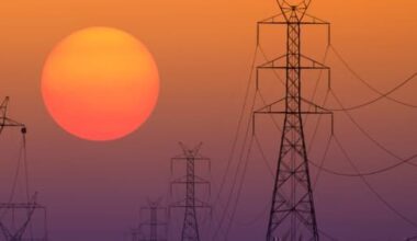 Power lines with a sunset behind in the distance.