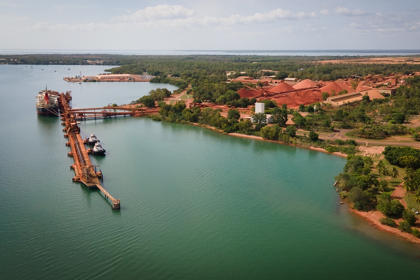 An aerial shot of a port in the tropics where a ship is being loaded.
