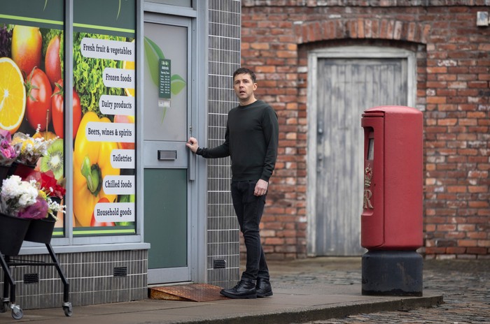 Todd stands alone outside of the corner shop in Coronation Street