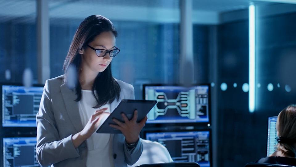 A businessperson is checking a tablet in an office.