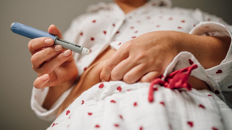 Close-up of woman administering insulin shot to stomach using injection pen.