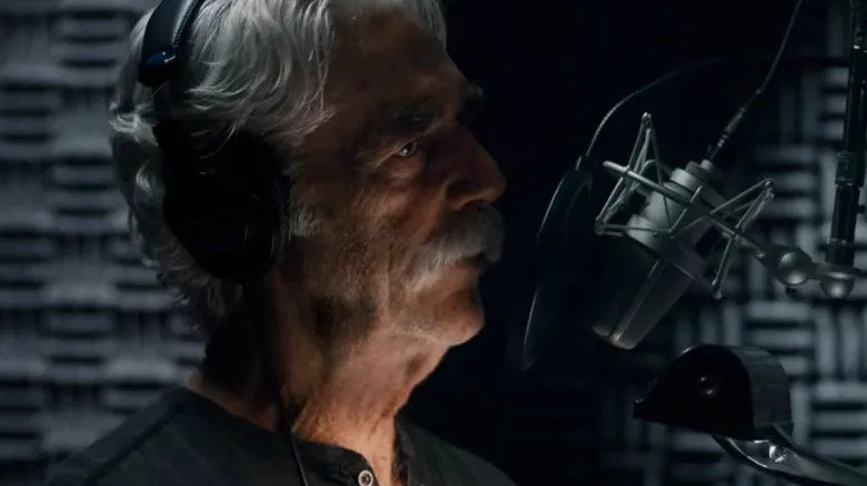 Sam Elliott's Lee Hayden stands in front of a microphone in a vocal booth in The Hero