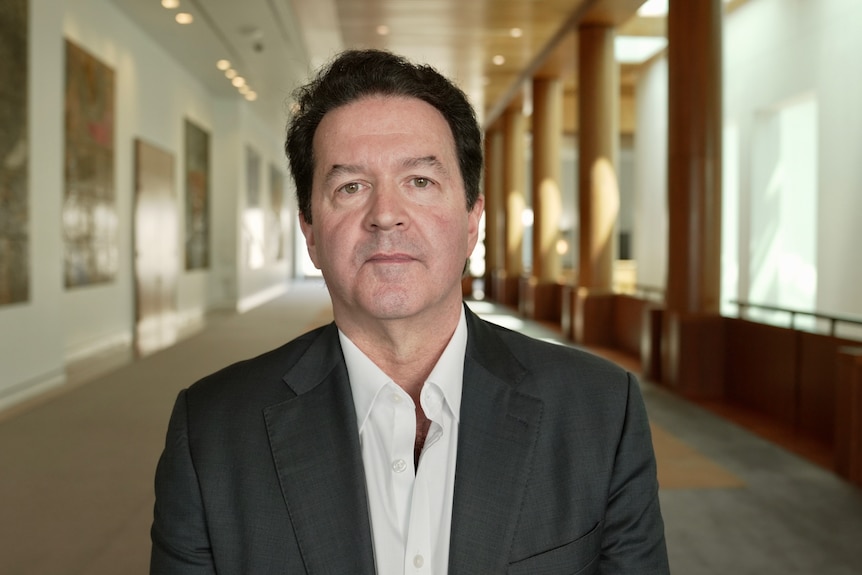 A man in a suit standing in a long hallway