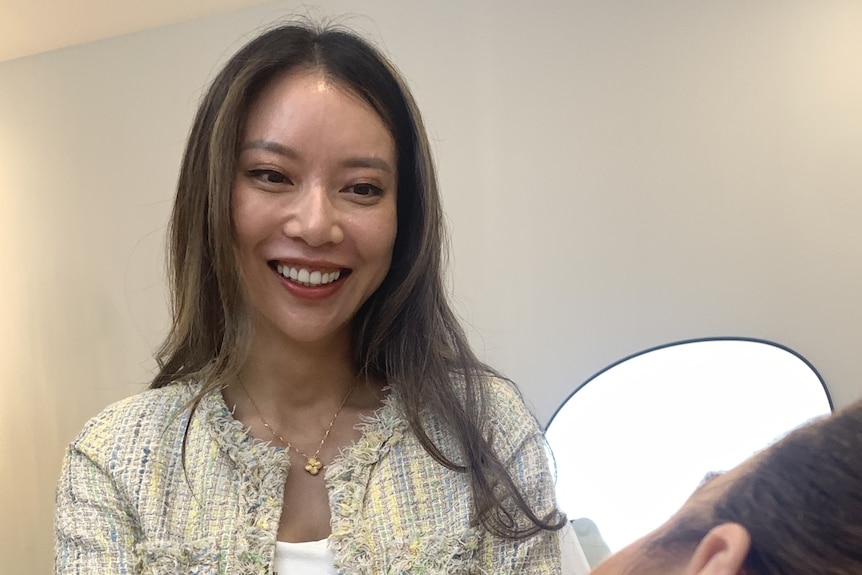 A woman smiles at another woman with her face turned away from the camera.