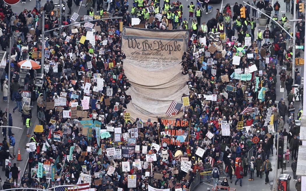 Protesters holding a large sign depicting the Declaration of Independence march near Times Square during the 