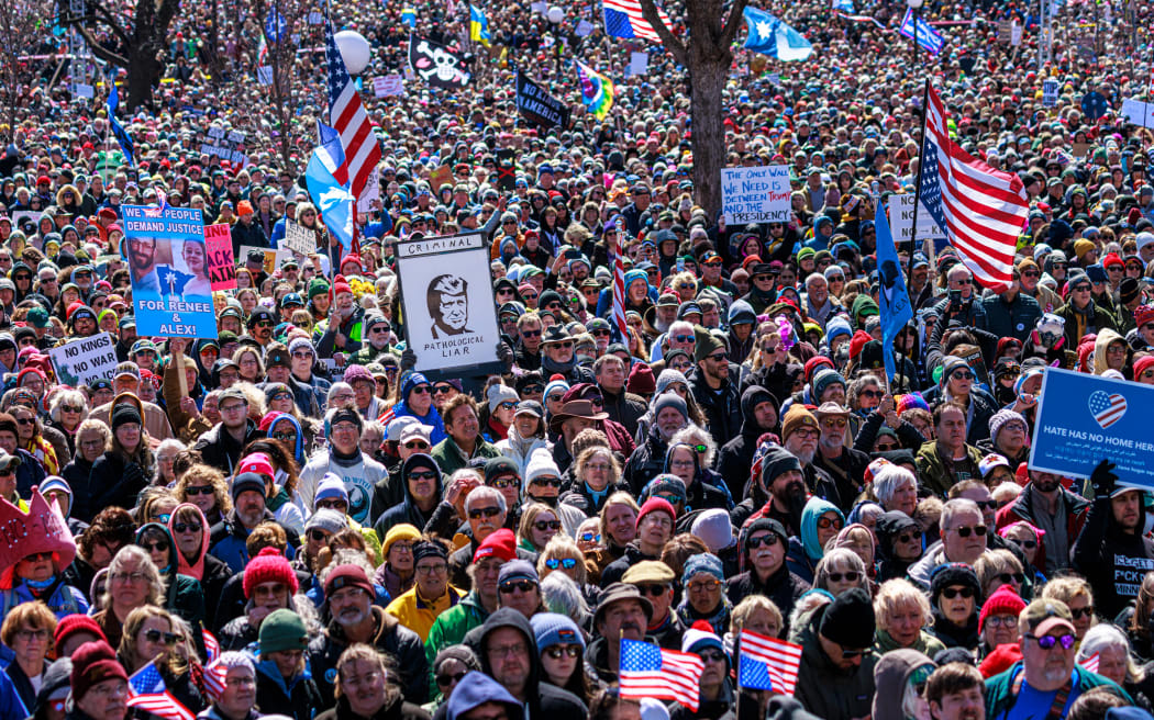People hold flags and signs as a large crowd gathers outside the Minnesota State Capitol during the 
