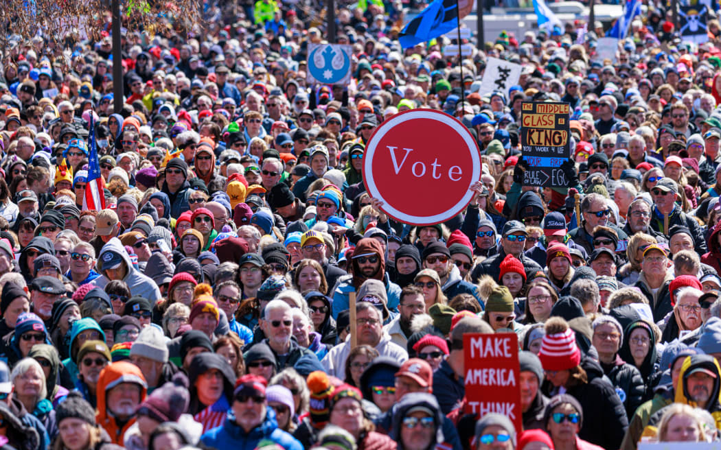 A person holds up a sign reading 