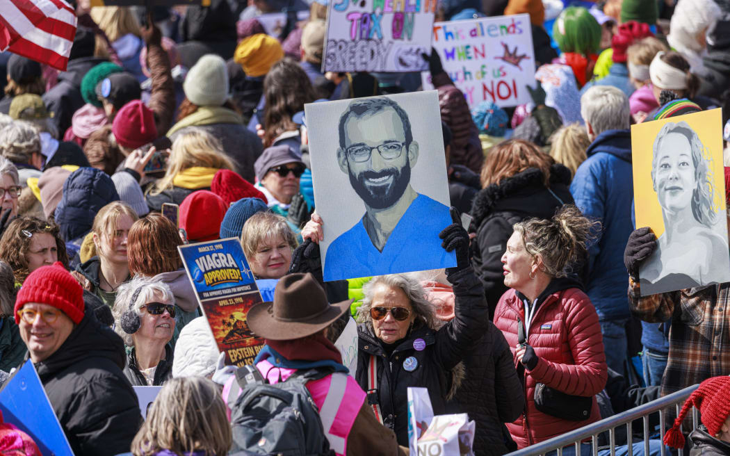 Images of Alex Pretti and Renee Good are displayed as a large crowd of demonstrators gather outside the Minnesota State Capitol during the 
