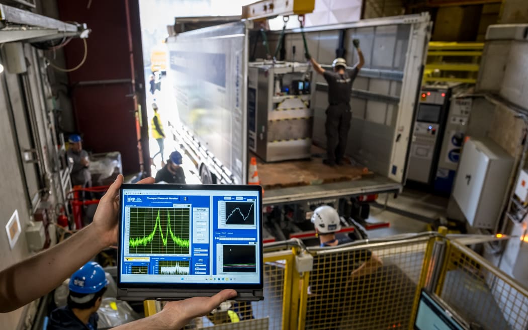 A specially designed portable cryogenic Penning trap device filled with a cloud of 92 antiprotons is transferred onto a truck during a successful test drive of the world’s first antimatter delivery system, conducted by CERN’s BASE-STEP experiment, which transported antiprotons by road across the organization’s main site, in Meyrin near Geneva, on March 24, 2026. The ultimate goal is to transport antiprotons to facilities such as Heinrich Heine University in Dusseldorf, where a calmer magnetic environment would enable measurements with greater precision. Such advances could provide crucial insights into one of the fundamental questions of physics: why matter dominates over antimatter in the universe. (Photo by Fabrice COFFRINI / AFP)