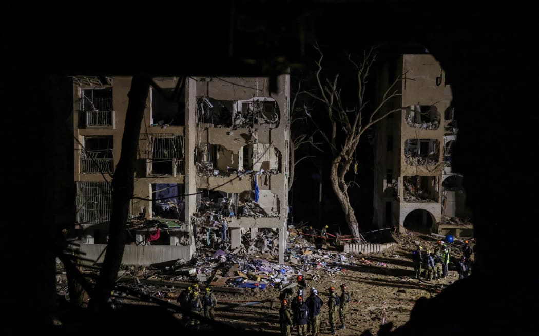 First responders inspect the site of an Iranian missile strike in Arad early on March 22, 2026. Iranian missile strikes on two southern Israeli towns wounded more than 100 people on March 21, medics said, after Israeli air defence systems failed to intercept the projectiles. (Photo by Ilia YEFIMOVICH / AFP) /