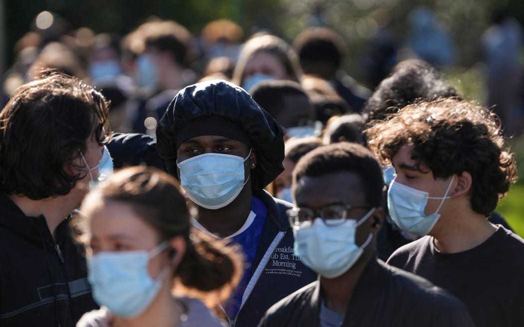 Students wearing face masks queue up to get vaccinated at the University of Kent in Canterbury, south-east England on March 18, 2026, following an outbreak of meningitis. Hundreds of masked-up students queued on March 18 to get vaccinated at the UK university campus at the heart of a deadly meningitis outbreak, as the number of cases rose to 20. (Photo by CARLOS JASSO / AFP)