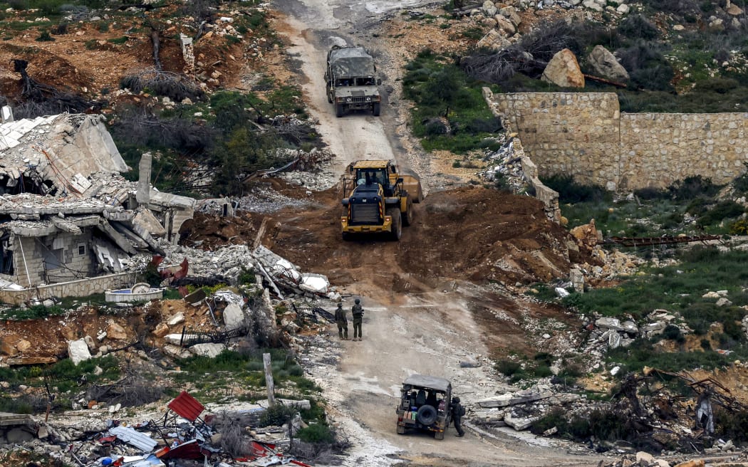 Israeli soldiers and a bulldozer conduct an operation in a southern Lebanese village along the border, as seen from a position in the Upper Galilee in northern Israel on March 18, 2026. The Israeli military said it planned to strike bridges and crossings over the Litani River in southern Lebanon on March 18 to disrupt what it said were Hezbollah arms-smuggling routes. Lebanon was drawn into the Middle East war on March 2 when militant group Hezbollah launched rockets into Israel to avenge the killing of Iran's supreme leader.