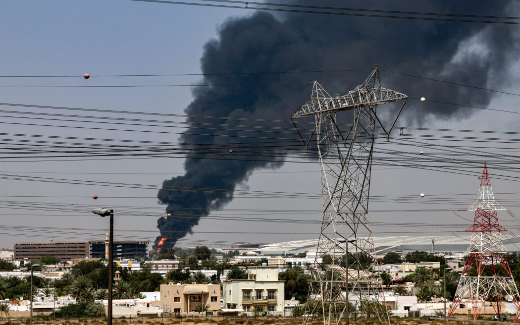 A smoke plume rises from an ongoing fire near Dubai International Airport in Dubai on March 16, 2026. Flights were gradually resuming at Dubai airport on March 16, previously the world's busiest for international flights, the airport operator said, after a "drone-related incident" sparked a fuel tank fire nearby, as Iran kept up its Gulf attacks. (Photo by AFP) /