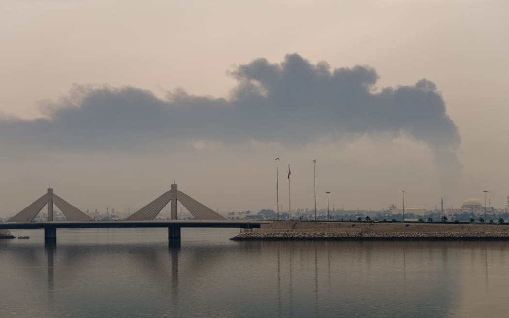 A plume of smoke rises after a reported Iranian strike on fuel tanks in Muharraq on March 12, 2026. Oil soared above $100 and stocks sank on March 12 as Iran's fresh attempts to hit supplies in the Middle East and threats to bring down the global economy overshadowed a record release of strategic crude by the International Energy Agency. Bahrain reported Iran had carried out an attack on fuel tanks in the country, while Saudi Arabia said it had intercepted drones headed to Shaybah oil field and drones struck fuel tanks at Oman's Salalah port, where operations were subsequently suspended.