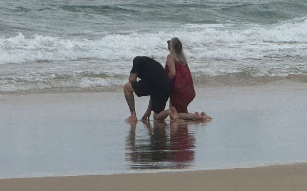 Angela and Todd James in the surf during smoking ceremony for Piper James on K'gari.