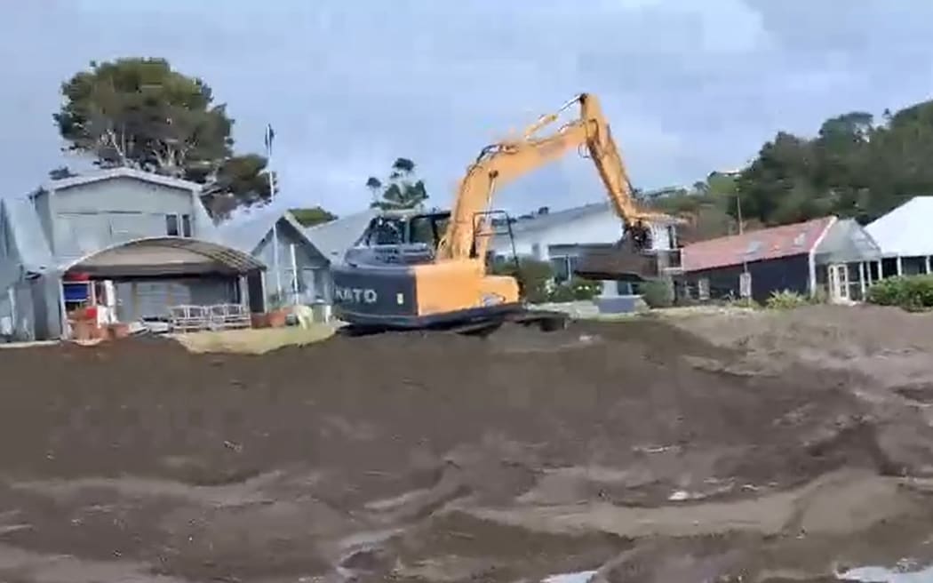 A still from a video taken by a local resident shows a digger at work on the beach at Church Bay, northeast of Whangārei.