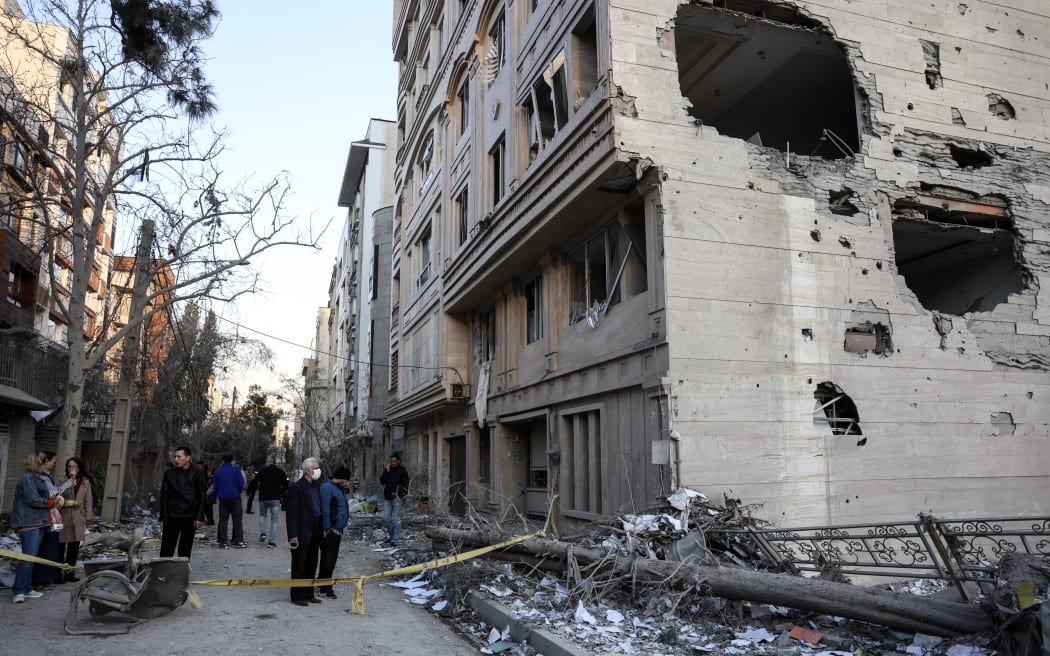 Residents stand on a street beside damaged residential buildings near Niloufar square in Tehran during the ongoing joint US-Israeli military campaign on Iran on March 2, 2026. The United States and Israel launched strikes against Iran on February 28, killing Iran's supreme leader and top military leaders, prompting authorities to retaliate with strikes on Israel and across the Gulf. (Photo by AFP)