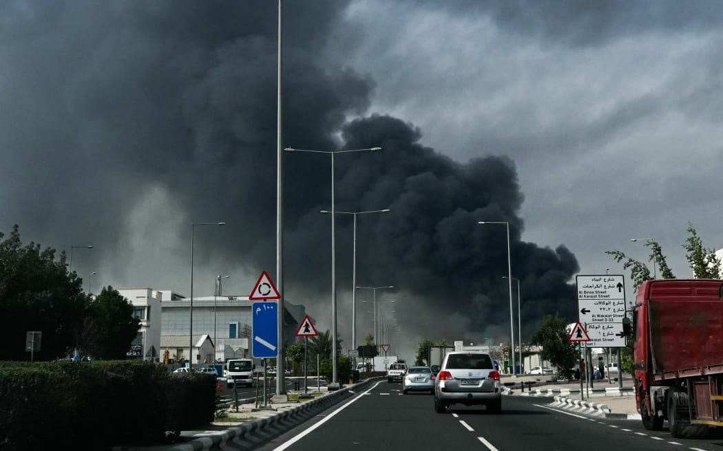 Motorists drive past a plume of smoke rising from a reported Iranian strike in the industrial district of Doha on March 1, 2026. US President Donald Trump said on February 28 that Iran's supreme leader Ayatollah Ali Khamenei was dead, after Israel and the United States launched an attack of unprecedented scale aimed at bringing down the Islamic republic. (Photo by Mahmud HAMS / AFP)