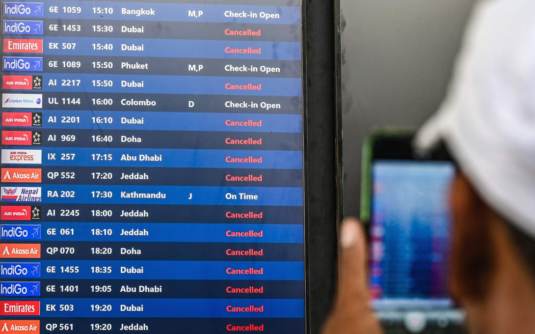 A passenger takes pictures of a flight information board at the Chhatrapati Shivaji Maharaj International Airport in Mumbai on March 1, 2026 after India's two largest private carriers IndiGo and Air India suspended flights to all destinations in the Middle East. Thousands of flights have been delayed or cancelled in the biggest disruption to global air transport since the Covid pandemic as airlines suspend services to the Middle East following the US and Israeli attacks on Iran. (Photo by Punit PARANJPE / AFP)