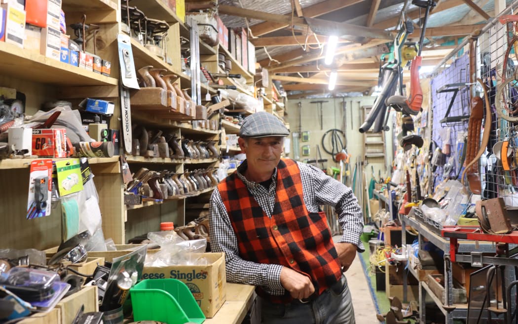 Photo of a man leaning next to a wall of tools.