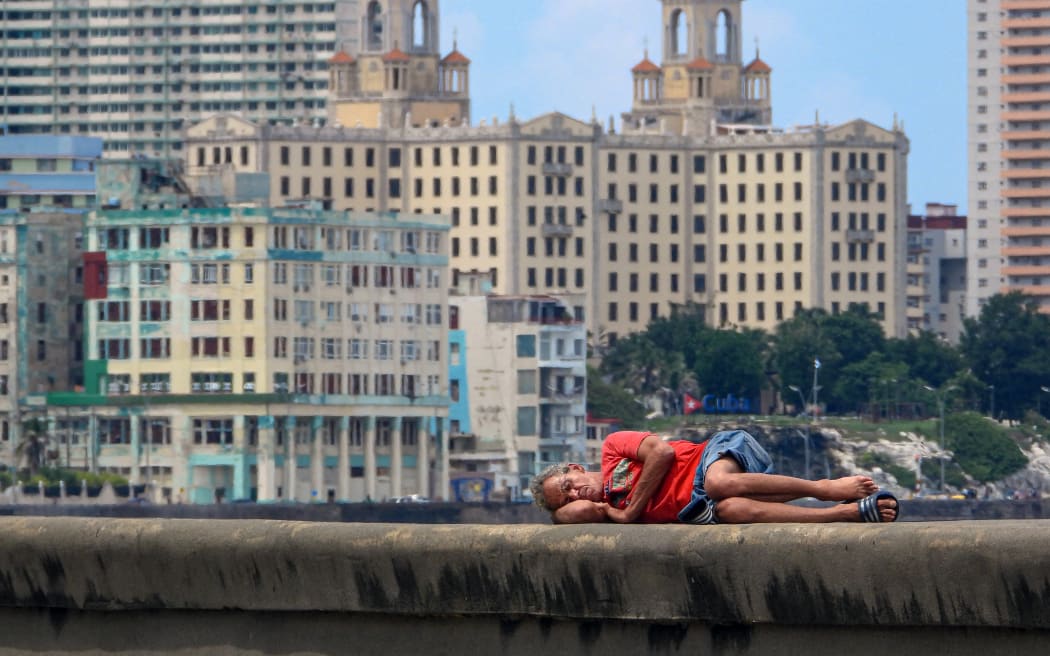 A man sleeps on Havana's Malecon waterfront on October 2, 2025. Poverty levels have risen sharply as Cuba faces its worst economic crisis in three decades, characterized by severe shortages of food, medicine, and fuel, along with daily power outages. (Photo by ADALBERTO ROQUE / AFP)