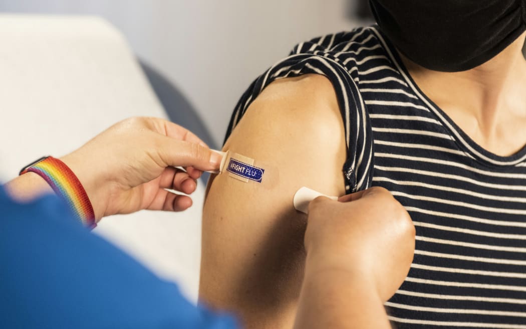 A medic applies a plaster, after a person has been given an influenza vaccine.