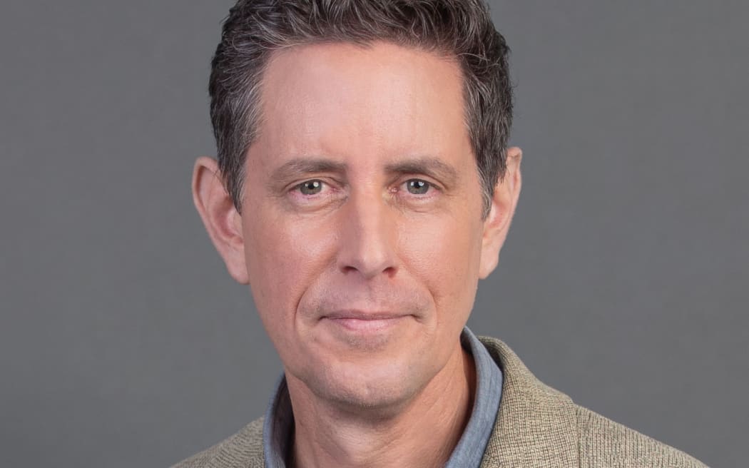 Relaxed smile portrait of Wallace Chapman on grey background