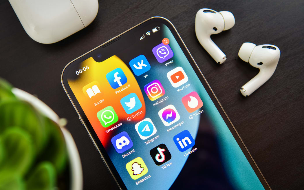 Social media icons on an iPhone screen with airpod headphones.