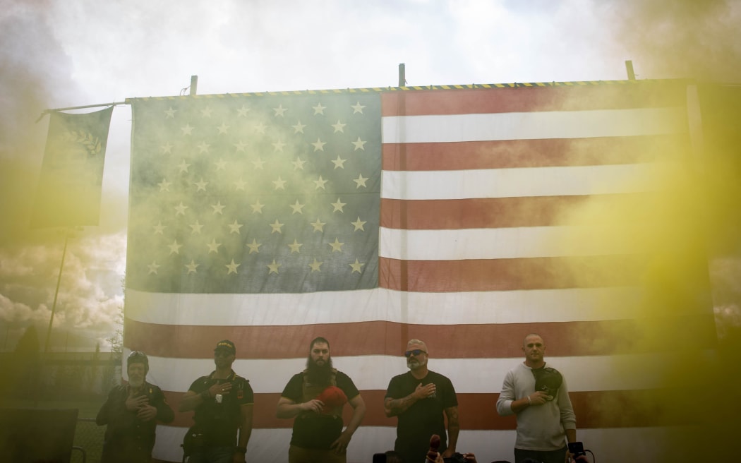 Yellow smoke fills the air as an American flag is raised at the start of a Proud Boys rally at Delta Park in Portland, Oregon on September 26, 2020.