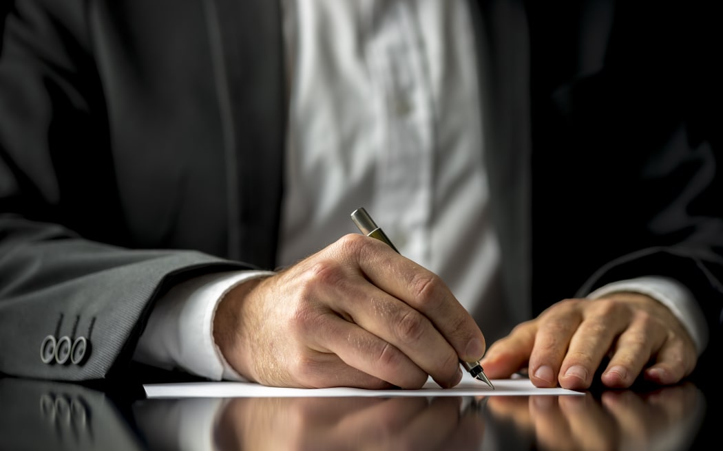A man signing a last will and testament document.